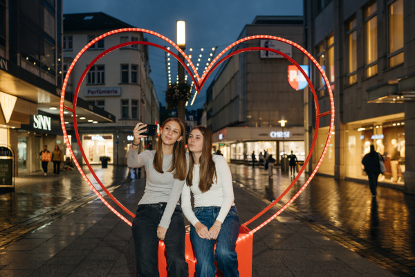 zwei Teenager-Mädchen machen Selfies in einem Herz