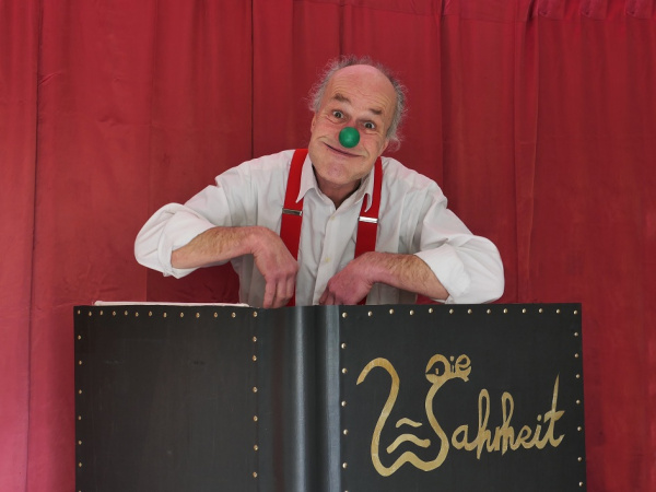 Mann mit Clownsnase hinter einem riesigen Märchenbuch