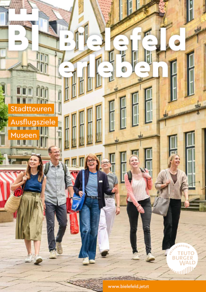 Gruppe von Touristen auf einem Platz in einer historischen Altstadt mit farbigen Geb&auml;uden.