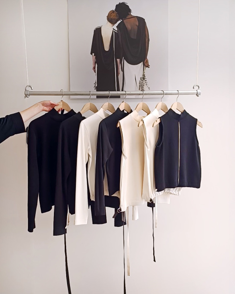 Aufnahme einer Kleiderstange mit schwarzer und weißer Kleidung. Minimalistisch vor weißer Wand