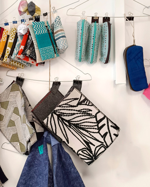 Unterschiedliche Taschen hängen an Drahtbügeln vor einer weißen Wand