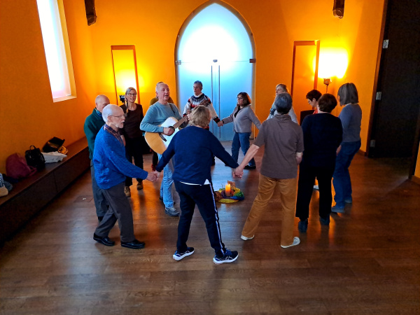 Menschen singen und bewegen sich im Kreis in der Capella Hospitalis