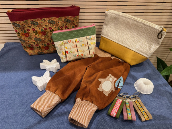Das Bild zeigt drei selbstgenähte Taschen, eine Babyhose sowie drei Schlüsselanhänger aus Filz