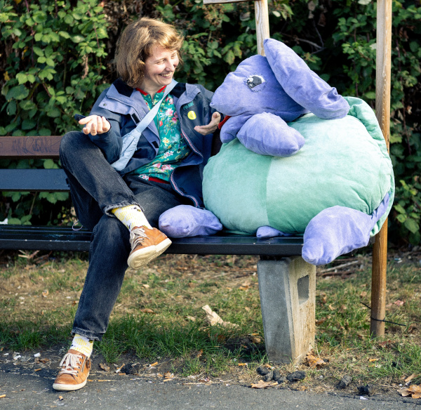 eine Person sitzt mit der Quartiers-Schildkröte Schildi auf einer Bank und unterhält sich