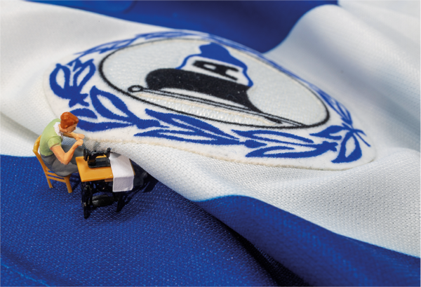 Eine Miniaturfigur näht eine Arminia-Fahne.