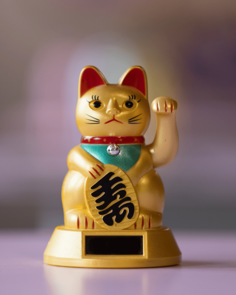 Goldene Glückskatze/Winkekatze auf einem Ausstellungssockel
