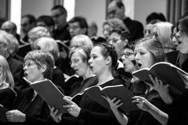Das Schwarzweißfoto zeigt singende Chorsänger*innen in der Rudolf-Oetker-Halle
